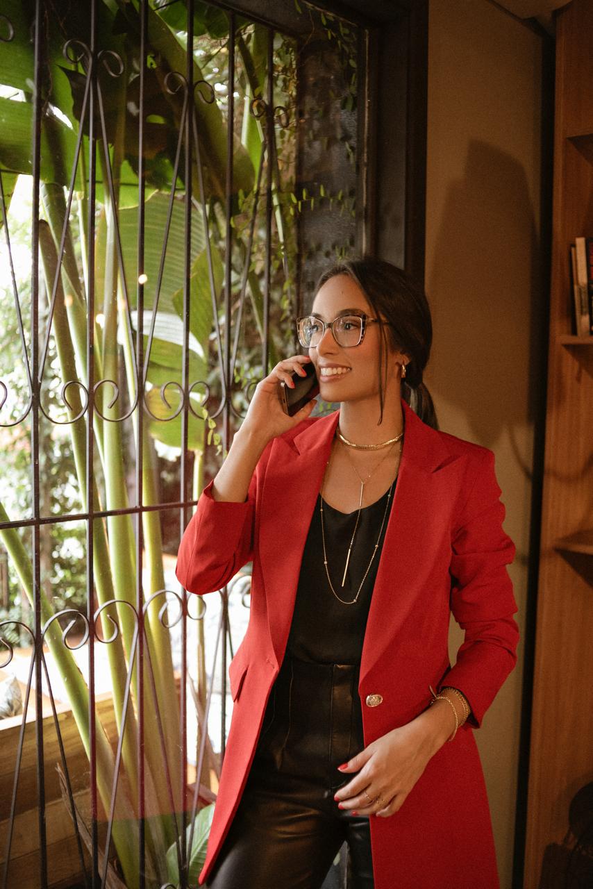 Advogada Amanda Nunes vestindo terno vermelho e falando ao telefone